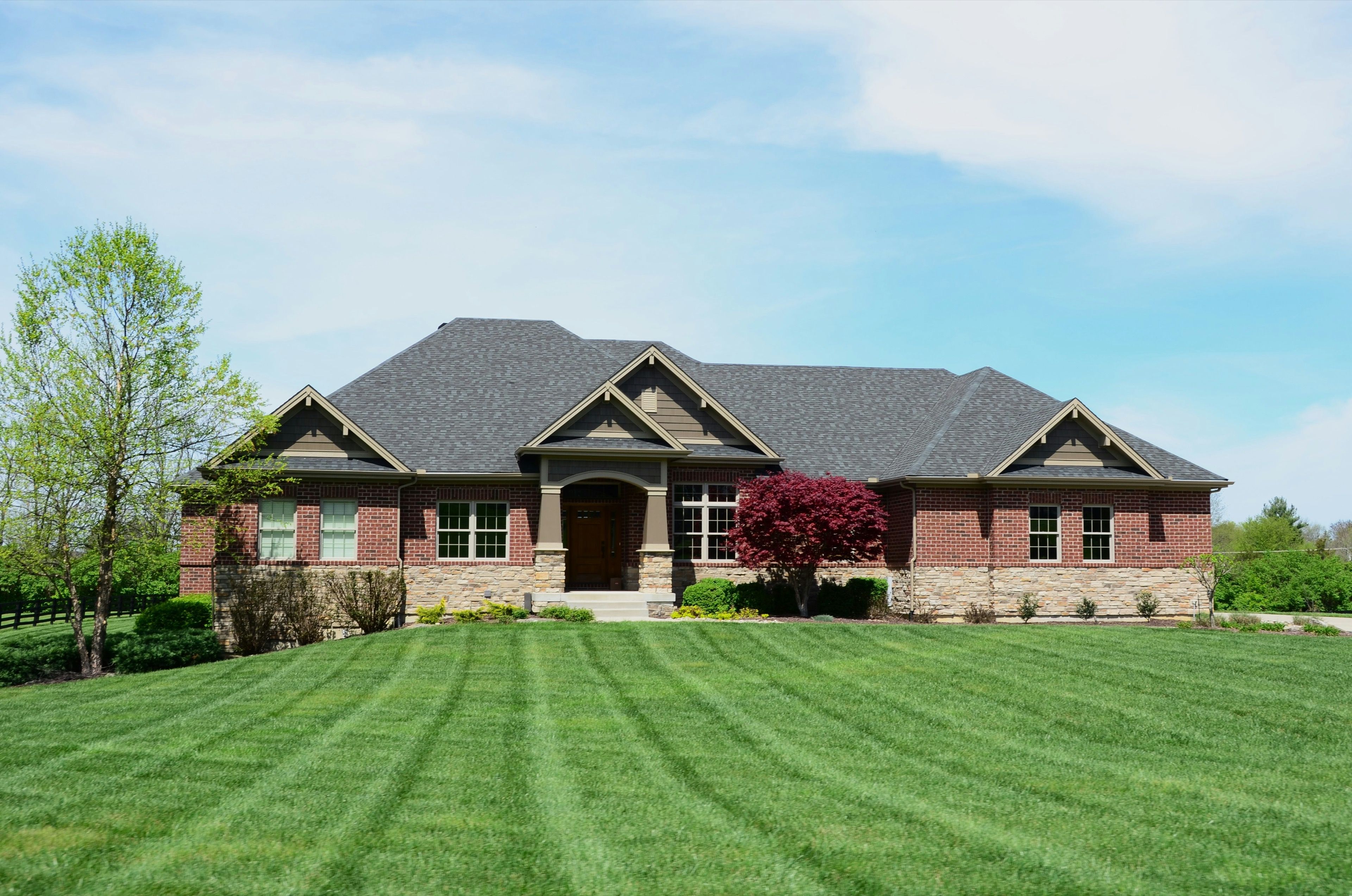 A freshly striped front lawn in front of a brick and stone home